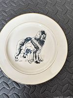 Front view of plate showing blue illustration of girl with Newfoundland dog and gold rim