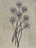 Full view of metal flower wall décor on ground