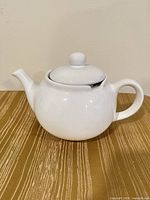Front view of white ceramic teapot with lid attached