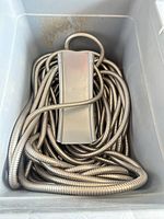 Coiled stainless steel hose with holder visible in plastic tote