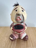 Front view of ceramic caricature coin bank showing slot labelled "RETIREMENT FUND" and overall paint condition
