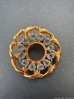 Front view showing gold-tone leaf setting and clear rhinestones