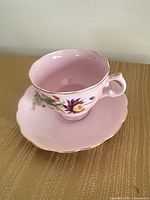 Teacup on saucer angled view showing floral design and gold rim