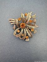 Front view of gold-tone thistle brooch showing amber stones and design details