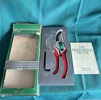 Outer green box, inner tray with pruner, accessories and manual visible