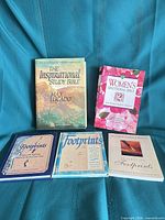 All five books laid out: Lucado Study Bible, Women's Devotional Bible, and three Footprints titles