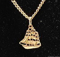 Close-up of gold sailing ship pendant on chain