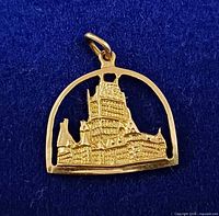Front view of gold pendant showing castle design and arched frame