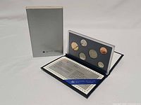 Open presentation case showing six coins, certificate and outer sleeve