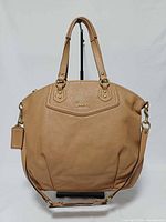 Front view of Coach tan leather satchel showing logo, handles, strap, hangtag