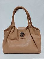 Front view of tan leather satchel showing flap and logo hardware