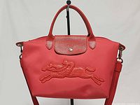 Front view of red Longchamp Cavalier tote showing embossed horse motif and overall design