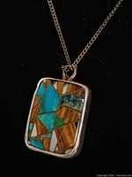 Close-up of rectangular turquoise and tiger's eye inlay pendant in sterling silver setting