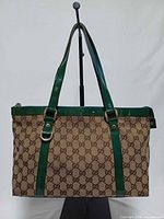 Front view of Gucci GG monogram tote with green patent leather trim and straps