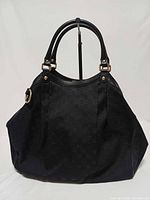 Front view of black Gucci Sukey GG monogram jacquard tote handbag on stand
