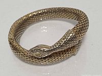 Full view of coiled snake mesh bracelet showing head detail and overall finish