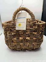 Three-quarter front view of woven bulrush bin showing hang tag and braided handle