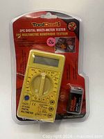 Front view of sealed ToolDeal DT-830B yellow multimeter and included 9 V battery in blister pack