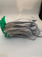 Stack of white cotton knit gloves with green cuffs side view