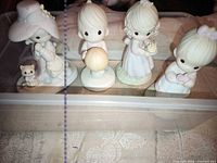Front view of four Precious Moments figurines in plastic bin