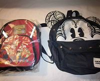 Front view of both backpacks, one sealed red Looney Tunes Blues, one black Mickey Mouse