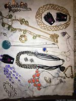 Overview of assorted necklaces, bracelets, earrings and pins laid out on fabric