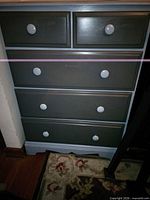 Front view of gray two-tone dresser showing five drawers and white round knobs