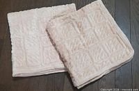 Pair of folded velvety pink mats on dark wood floor