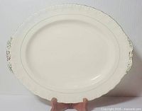 Front of oval cream platter with green border and handle motifs