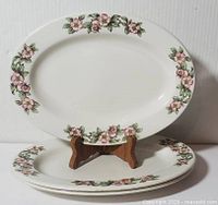 Three oval plates stacked and displayed on stand showing Apple Blossom border