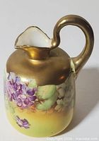 Front view showing floral motif, gold handle and gradient body