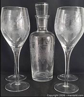 Full view of decanter with stopper and four goblets showing etched grape design