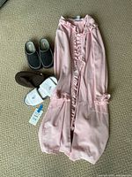 Pink bathrobe laid out with three pairs slippers