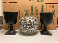 Full view of two black urn vases and one ceramic swirl vase