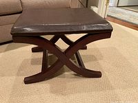 Full view of footstool showing cushion and X-legs