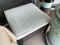 Top view of ottoman with cushion and partial view of protective cover