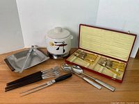 Group shot of bean pot on base, Bakelite set in case, fondue forks, salad servers, carving fork, appetizer forks and tray