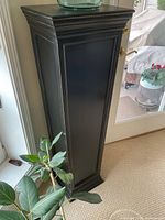 Full view of black wood pedestal next to door