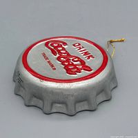 Front angled view showing red Coca-Cola logo, silver finish, gold string