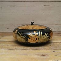 Front view of lidded wooden bowl showing swan motifs