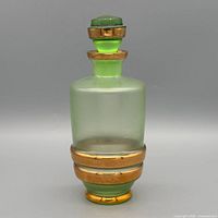 Full view of pale green frosted glass decanter with stopper showing gilt bands