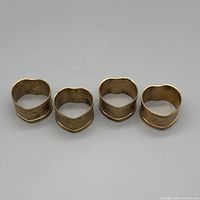 Top view of four brass heart napkin rings
