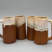 All four brown stoneware steins with white drip glaze displayed together
