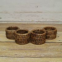 Front view of four woven rattan napkin rings in a row