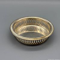 Angled view showing entire round silver-plated coaster with pierced gallery