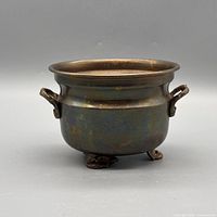 Front view showing cauldron shape, handles and feet