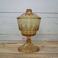 Front view of amber pressed glass compote with lid on pedestal