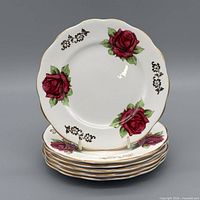 Stack of six Picardy Rose butter plates, top view showing rose motif and gilt trim