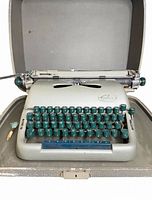 Front view of typewriter inside case showing keys, body, and case interior