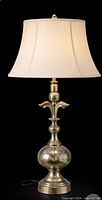 Full view of metallic sculpted table lamp with shade for staging